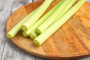 Board with fresh leeks on grey wooden background