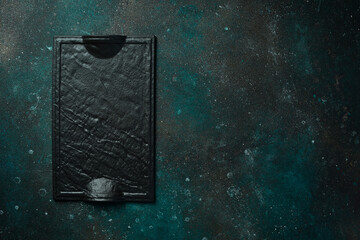 Square slate black plate. On a dark green-turquoise background. Free space for text.