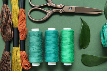 Set of different embroidery supplies on dark green background