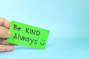 Be kind always and kindness reminder concept. Hand holding a bright green paper message note.
