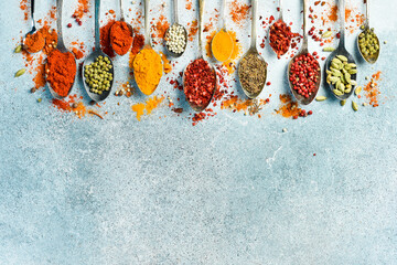 Banner of colored spices. Spoons with spices on a light stone background. Top view. Free space for...