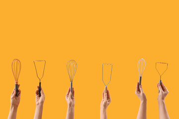 Female hands holding different whisks and mashers on yellow background