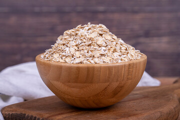 Oatmeal or Oat flakes on wooden background. Oatmeal in wooden bowl. Close up
