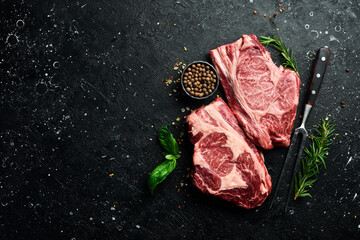 Two Raw fresh marbled meat Steak Ribeye and seasonings on dark wooden background. Meat. Top view. Free space for text.