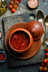Borsch. Beetroot soup in a clay jug. Traditional Ukrainian cuisine. Close-up, dark background.