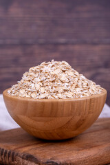 Oatmeal or Oat flakes on wooden background. Oatmeal in wooden bowl. Close up