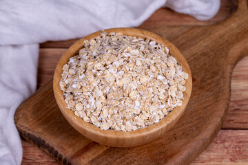 Oatmeal or Oat flakes on wooden background. Oatmeal in wooden bowl