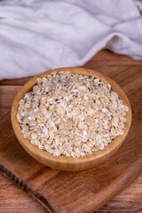 Oatmeal or Oat flakes on wooden background. Oatmeal in wooden bowl. Close up