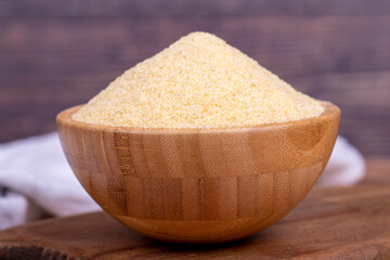 Dry organic semolina flour on wooden background. Uncooked organic semolina in wooden bowl. Close up
