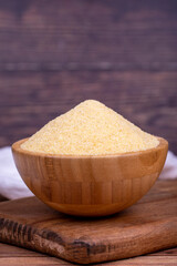 Dry organic semolina flour on wooden background. Uncooked organic semolina in wooden bowl