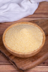 Dry organic semolina flour on wooden background. Uncooked organic semolina in wooden bowl. Close up