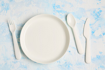 White plate with cutlery for baby on grunge blue background