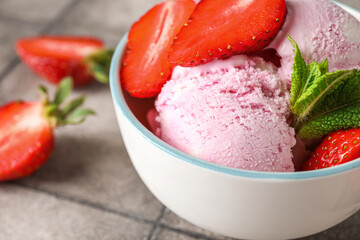 Bowl of delicious ice cream with fresh strawberries and mint on grey grunge table, closeup