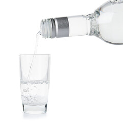 Pouring of vodka from bottle into glass on white background