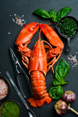 grilled lobster with lemon and basil on a black slate board. on a dark wooden table