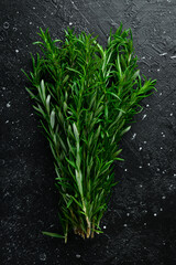 Fresh green rosemary. Spices. On a black stone background.