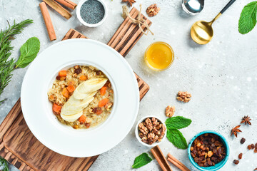 Breakfast. Oatmeal with dried fruits and banana. On a white plate. On a gray stone background. Restaurant menu.