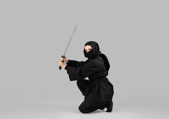 Female ninja with sword on grey background