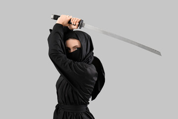 Female ninja with sword on grey background