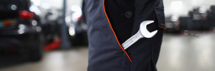 Wrench in pocket in uniform at locksmith in auto repair shop. Tool in special work clothes and car maintenance