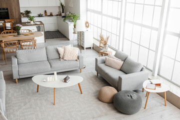 Fototapeta na wymiar Interior of light open plan kitchen with grey sofas and coffee table