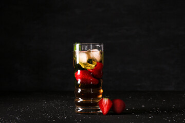 Glass of ice tea with strawberry and mint on black background