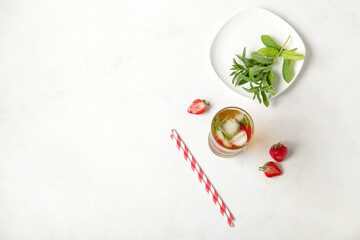 Glass of ice tea with strawberry and mint on white background