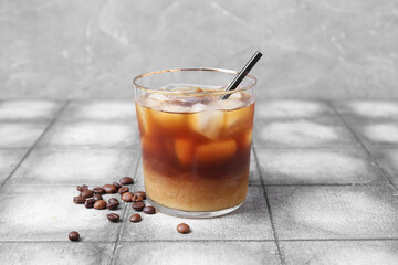 Glass of tasty ice coffee with milk on table