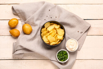 Bowls of tasty sour cream with sliced green onion and potato chips on white wooden background