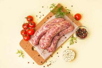 Board with raw fresh sausages, tomatoes and spices on beige background