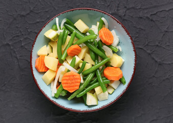 Bowl with fresh vegetables on black background