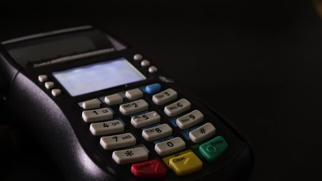 Person swiping card through dataphone and entering their secret pin to make a payment. Slow motion
