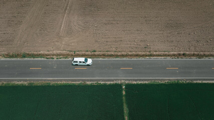 Obraz premium Aerial view of green field forest and white car on the road. Bird's eye.