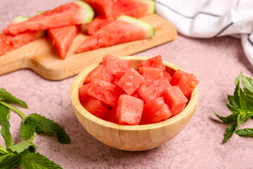 Board and bowl with pieces of fresh watermelon on pink background