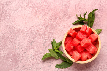 Bowl with pieces of fresh watermelon and mint on pink background
