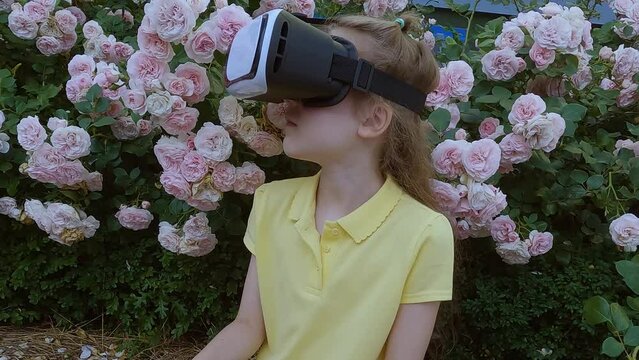 The girl is wearing a virtual reality helmet on her head. A girl plays in virtual reality glasses on the street.