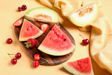 Board with pieces of fresh watermelon and different berries on yellow background