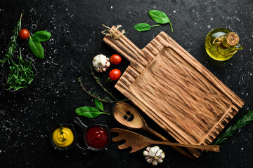 Obraz na płótnie Canvas Cooking background. Kitchen board, vegetables and spices. On a black stone background. Top view.