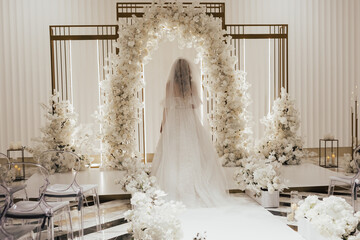 A bride in a white wedding long dress 
goes to luxury elegant wedding decoration.