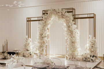 Wedding arch decorated with white flowers in the luxury restaurant. Beautiful wedding set up in the...