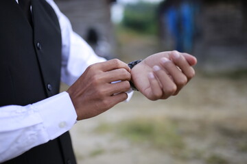 A man Puts on a shirt and a watch.
