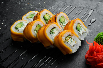 Classic sushi rolls with avocado, Philadelphia cheese, and cheddar cheese. Japanese food. On a black stone background. Top view.