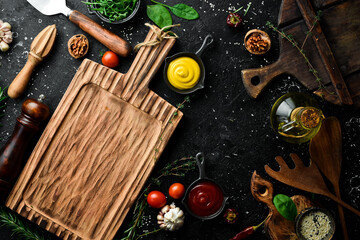 Naklejka na ściany i meble Cooking background. Kitchen board, vegetables and spices. On a black stone background. Top view.