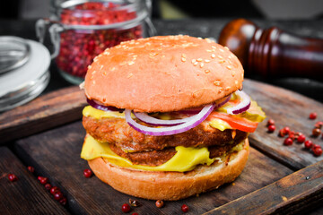 Classic cheeseburger with beef cutlet. Side view. On a wooden board.