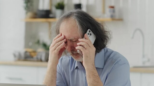 elderly frustrated man talking on the phone and heard the bad news, in upset feelings