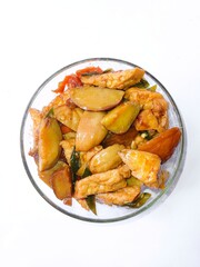 Sauteed jengkol and tofu in a glass bowl over a white background. Stir fried stinky bean or dogfruit (Archidendron pauciflorum) and tofu. Vertical shot