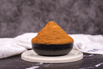 Cinnamon powder on dark background. Powdered dried cinnamon in bowl. Spice concept