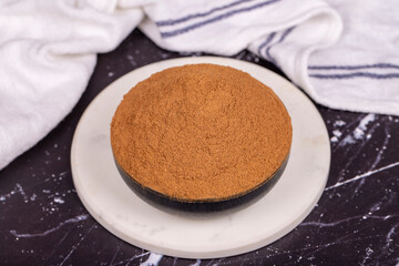 Cinnamon powder on dark background. Powdered dried cinnamon in bowl. Spice concept