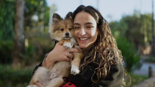 Young hispanic woman with dog smiling confident standing at park