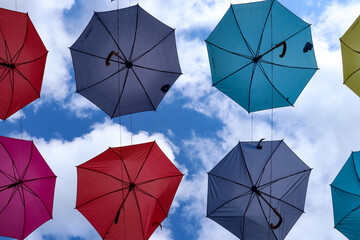 Kolorowe parasolki zawieszone nad deptakiem - obrazy, fototapety, plakaty